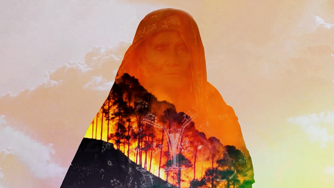 Double exposure of a woman in a hooded shawl layered with a burning forest
